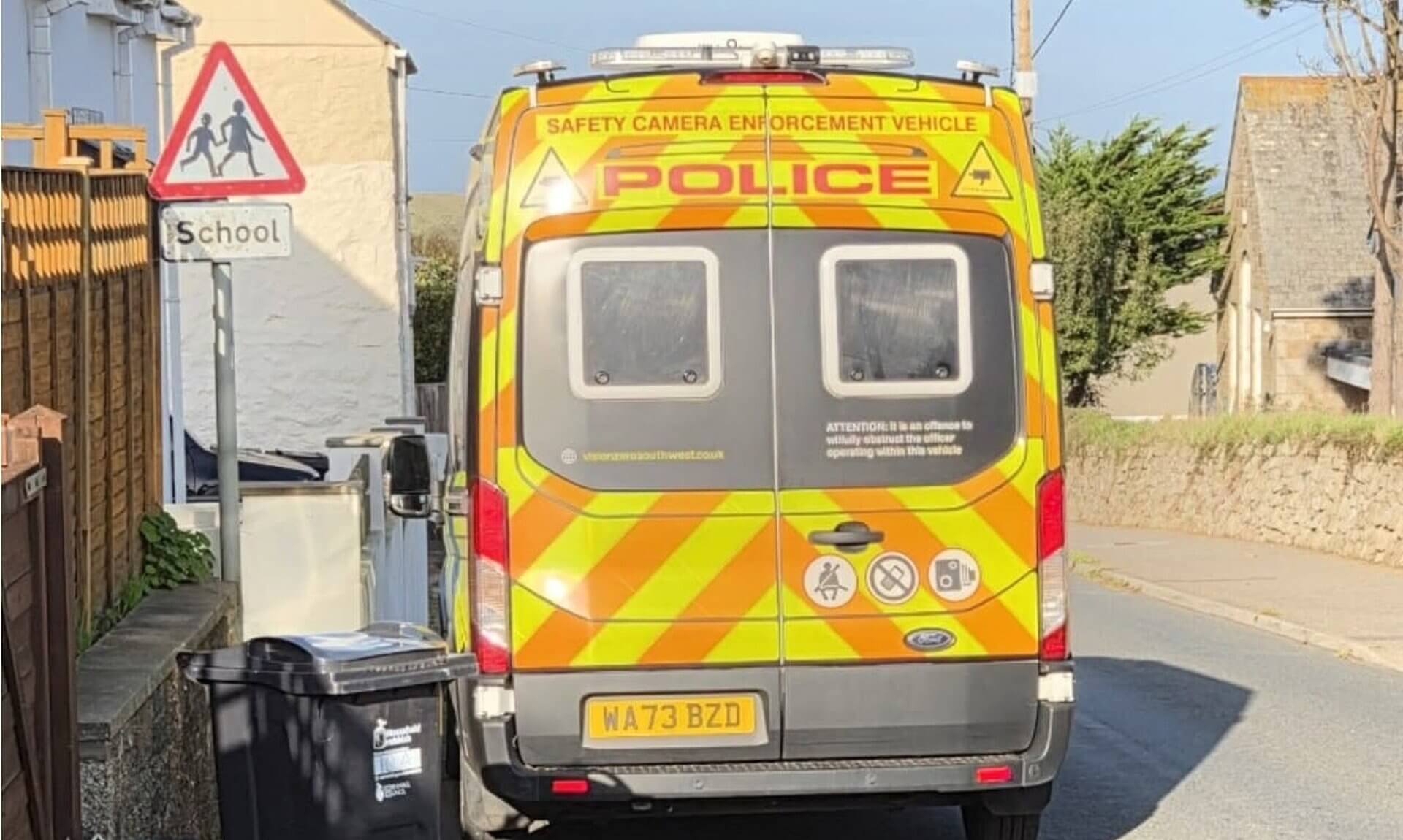 Police safety camera enforcement van parked beside a school warning sign