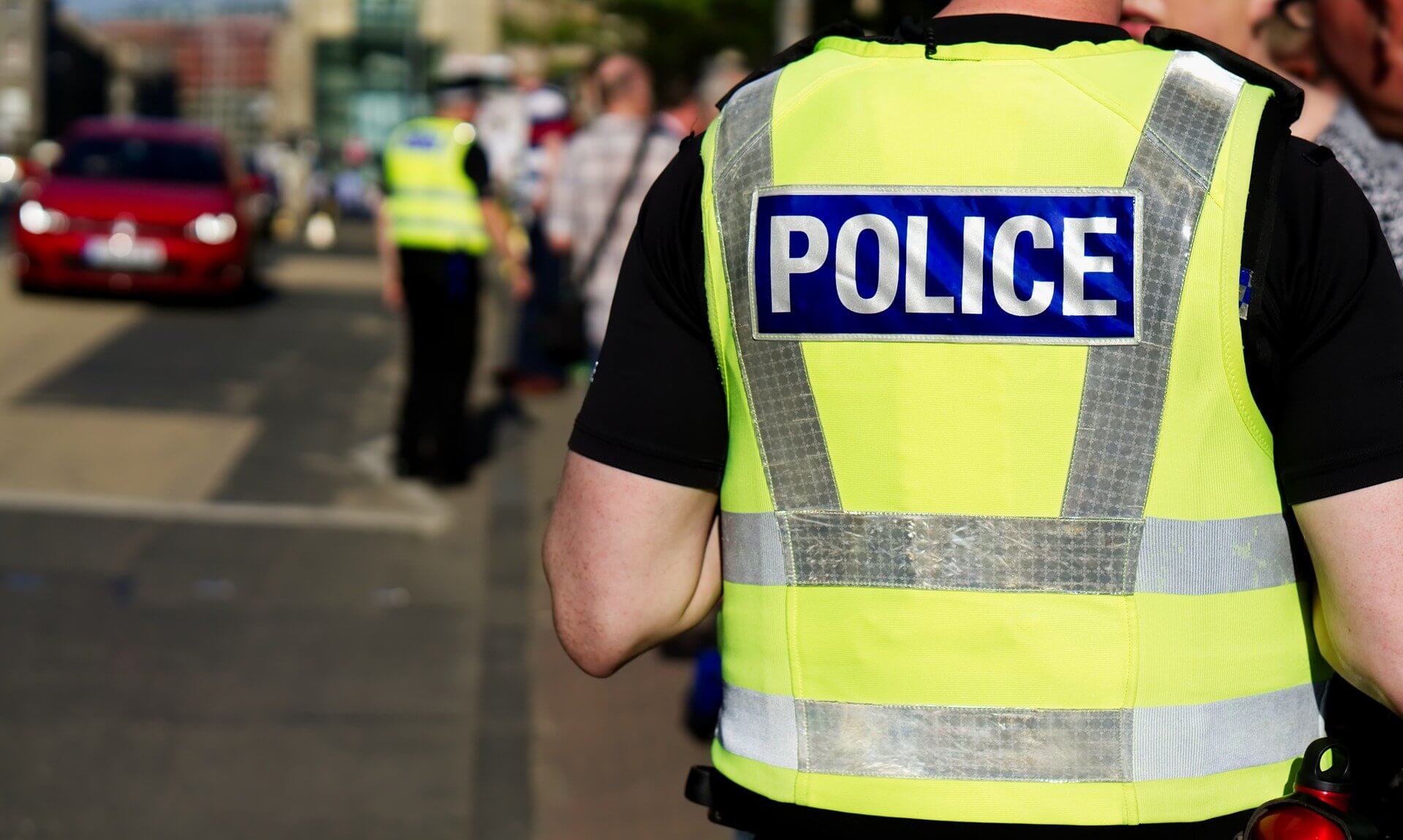 Police officer in a hi-vis vest seen from behind on a busy street