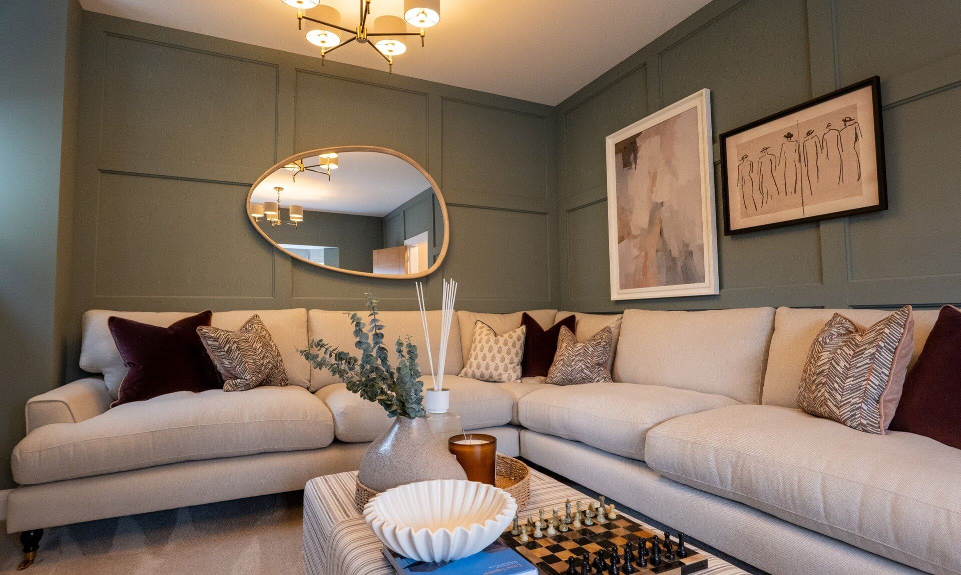 Living room with panelled green walls and a cream corner sofa in a Cavanna Homes showhome