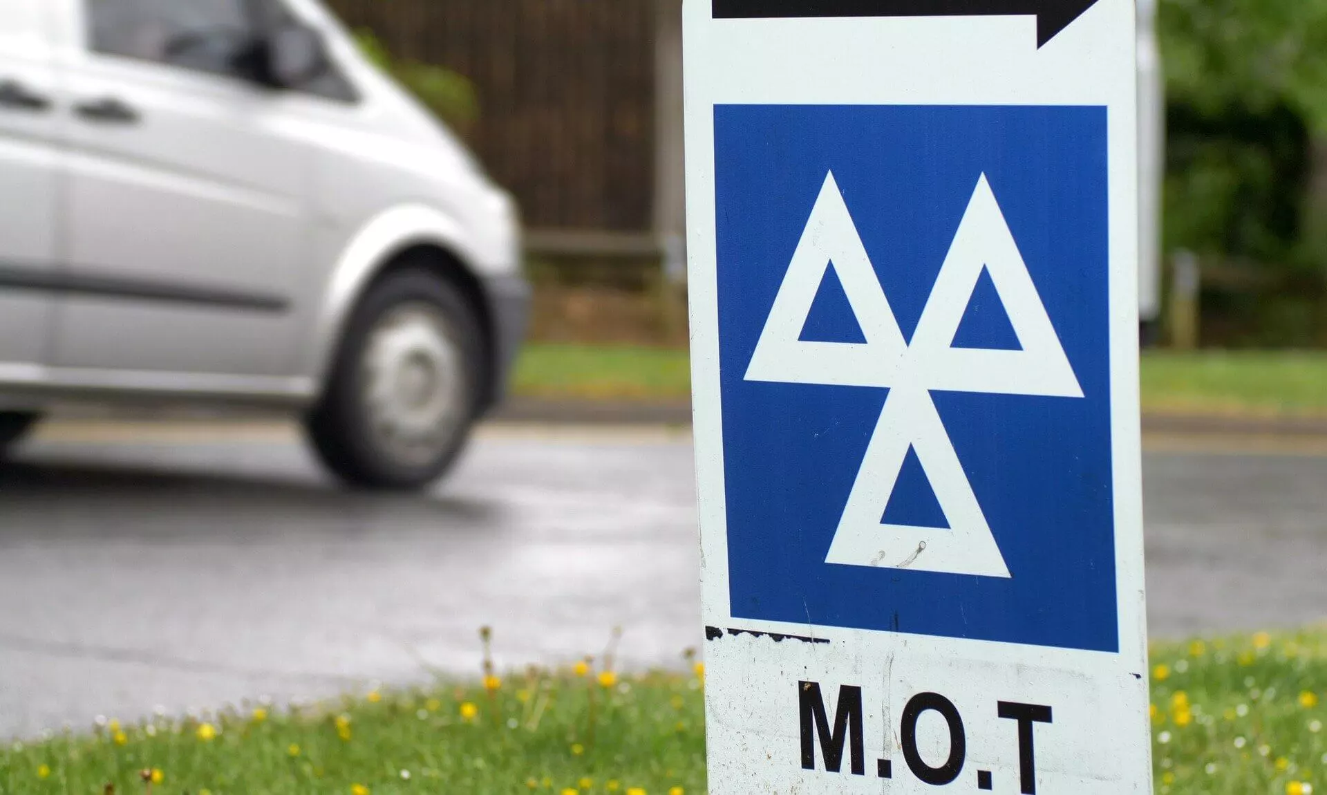 MOT test centre sign beside a road with a van passing