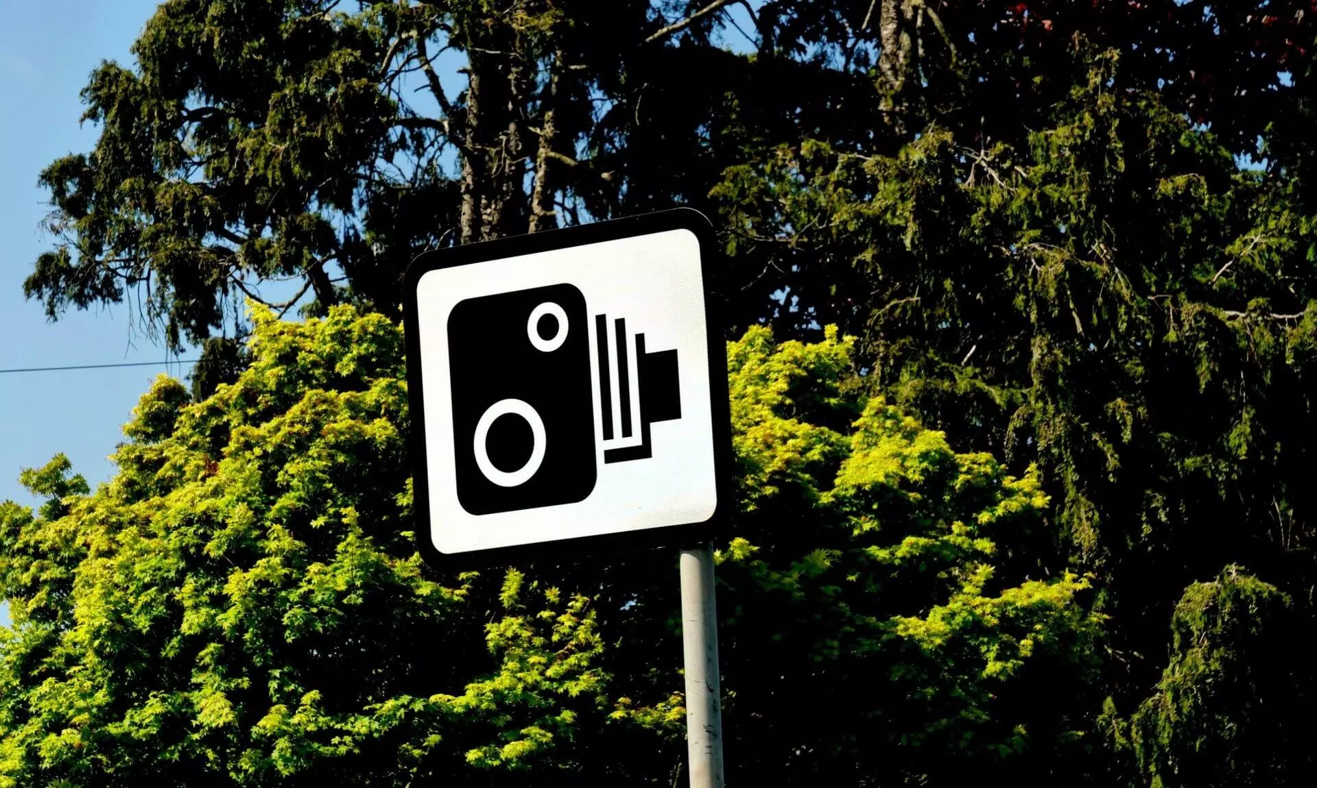 Speed camera warning sign in front of trees