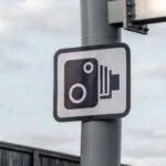 Speed camera warning sign on a roadside pole