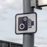 Speed camera warning sign on a roadside pole