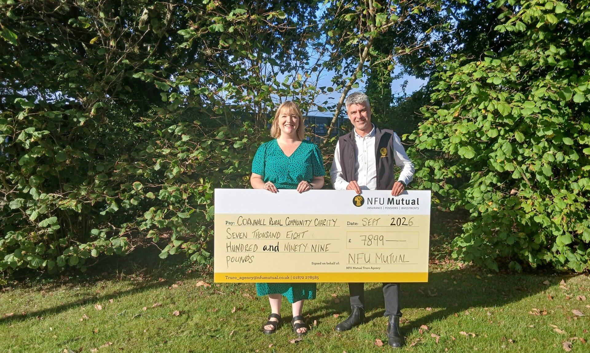 Katherine Nissen and Paul Shirley holding a large NFU Mutual cheque for £7,899 made out to Cornwall Rural Community Charity