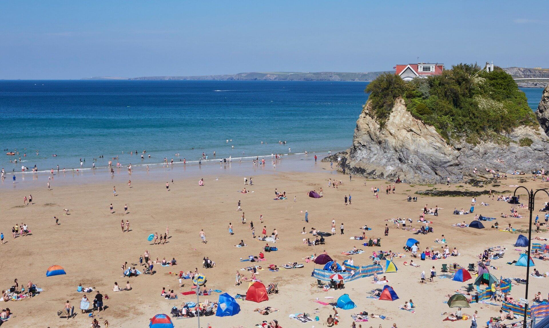 Busy summer day on Towan Beach in Newquay with The Island and its house on the rock
