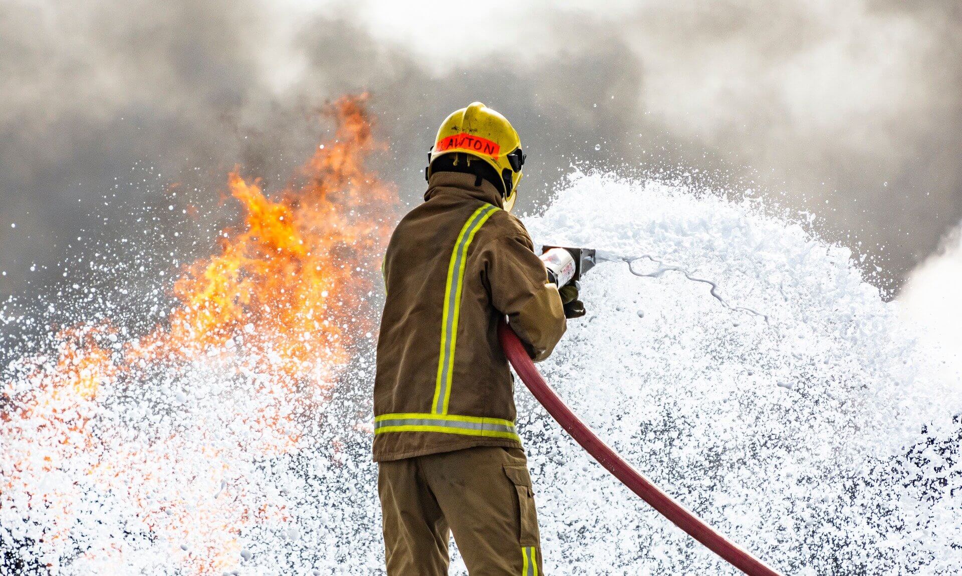 Firefighter tackling a blaze with a foam jet