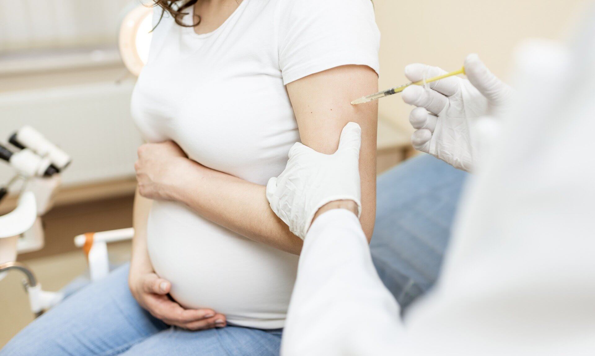 Pregnant woman receiving an injection in her upper arm in a clinic