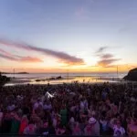 Crowds on the sand at Lusty Glaze, Newquay, as the sun sets over the Atlantic