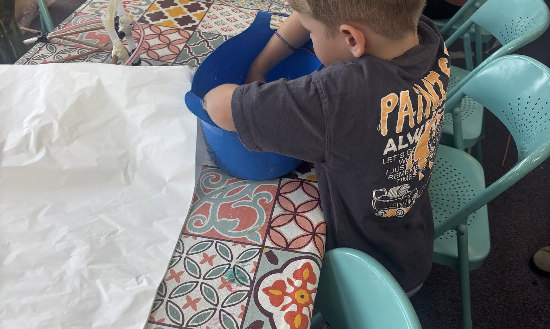 A child mixing paste in a blue tub at the Monster Making Workshop at Newquay Library
