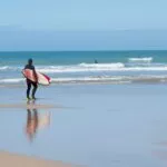 A surfer carrying a board walks towards the sea