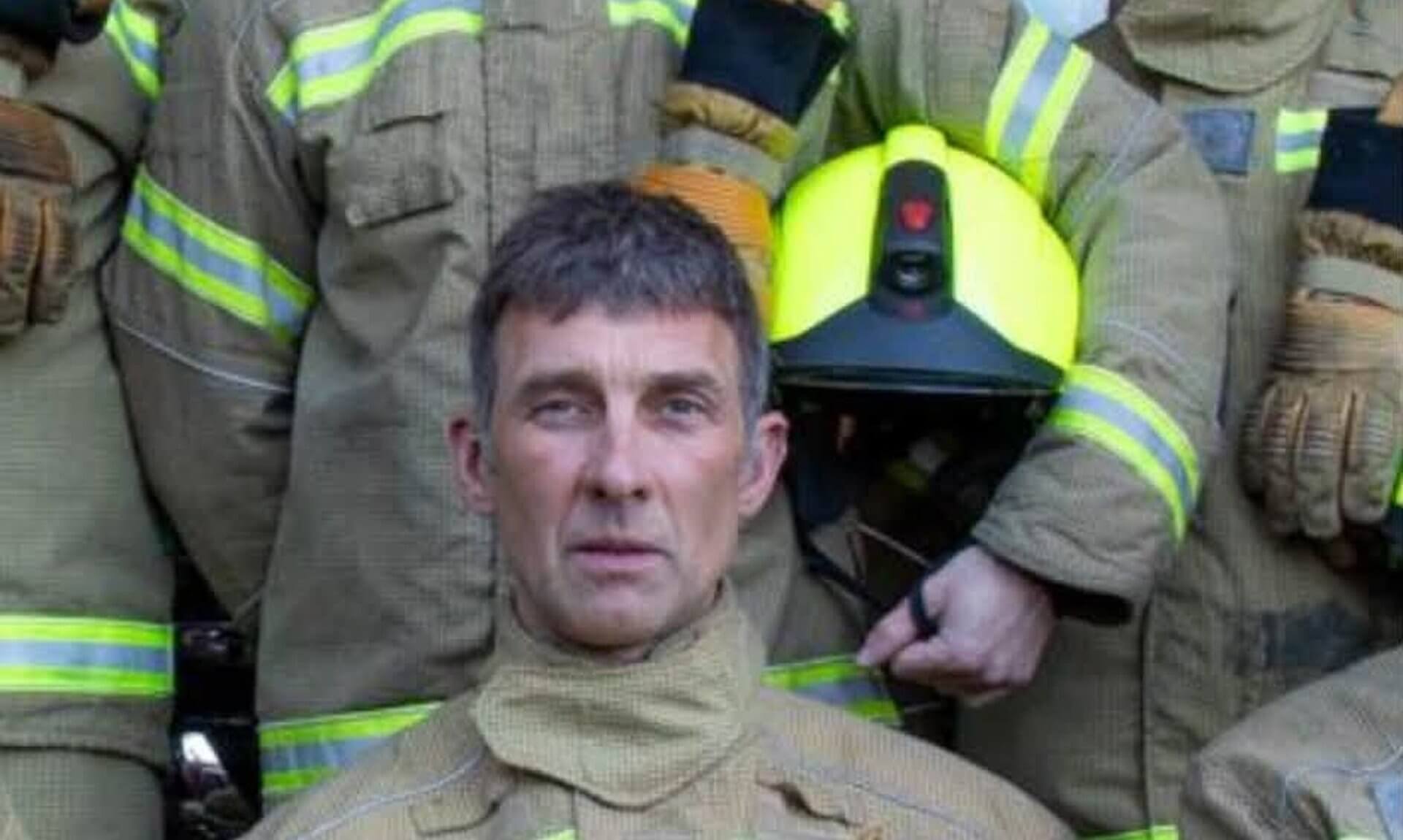 Firefighter in kit seated among crew at Mevagissey Fire Station