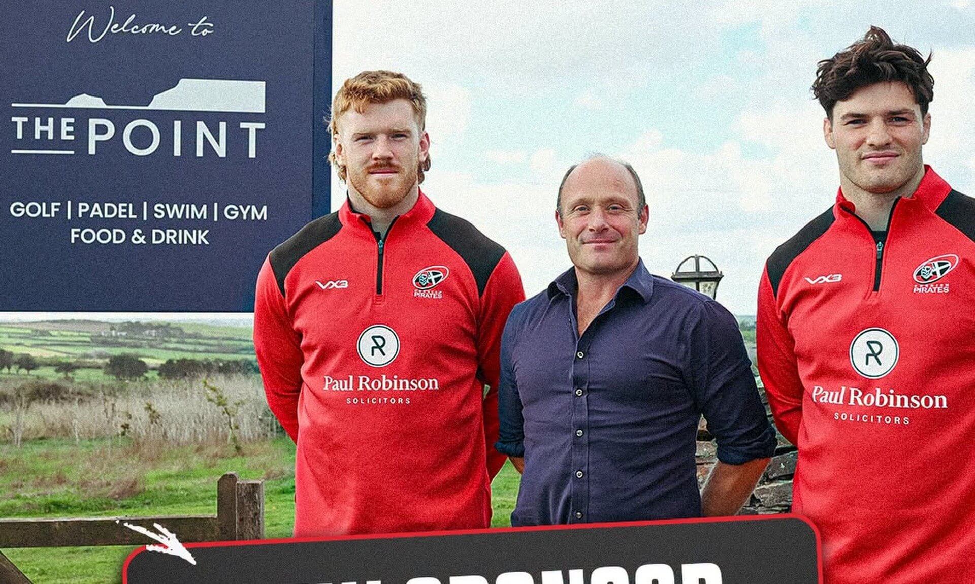 Two Cornish Pirates players with a representative of The Point at Polzeath beside the venue's welcome sign