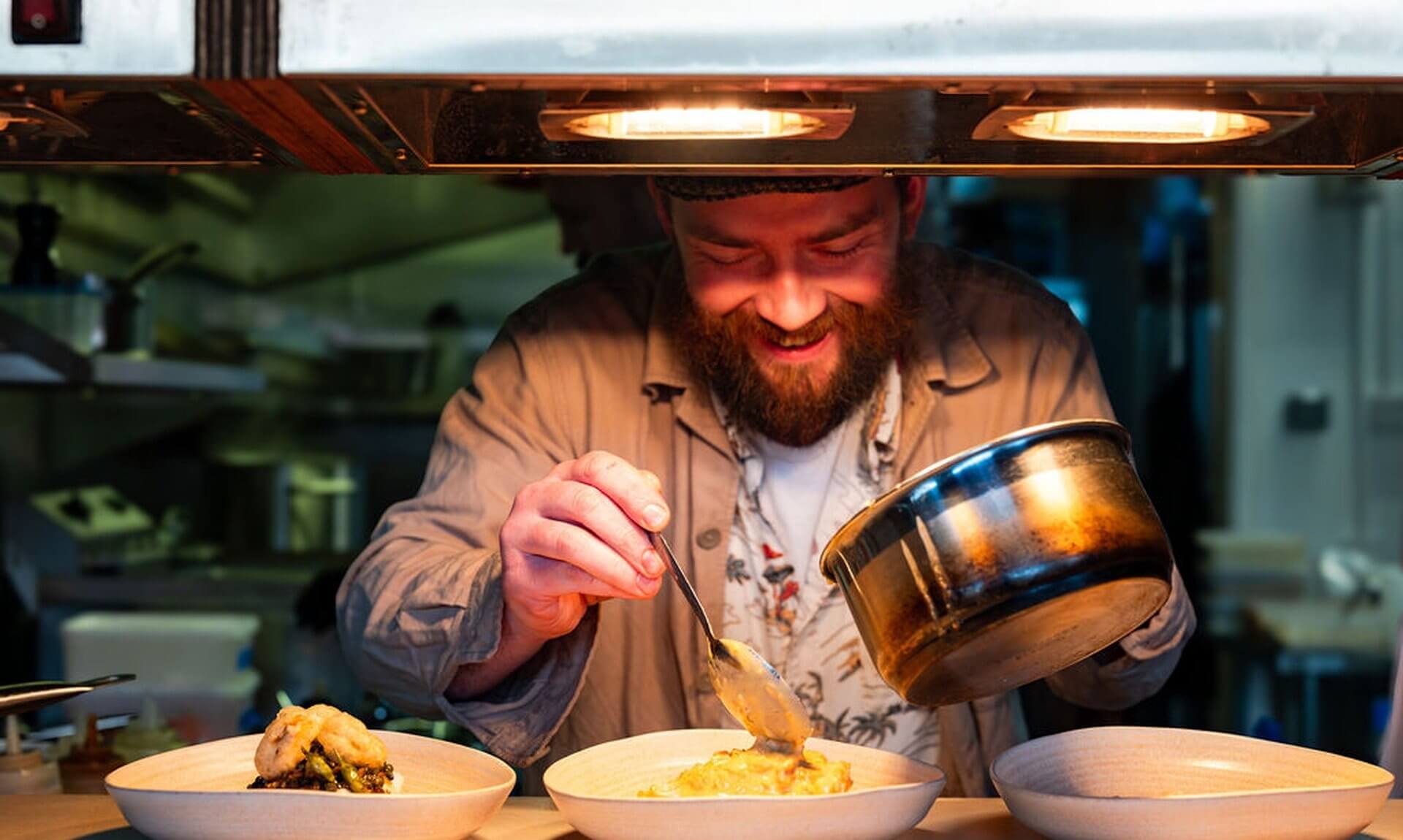 Chef plating dishes under the heat lamps at the pass