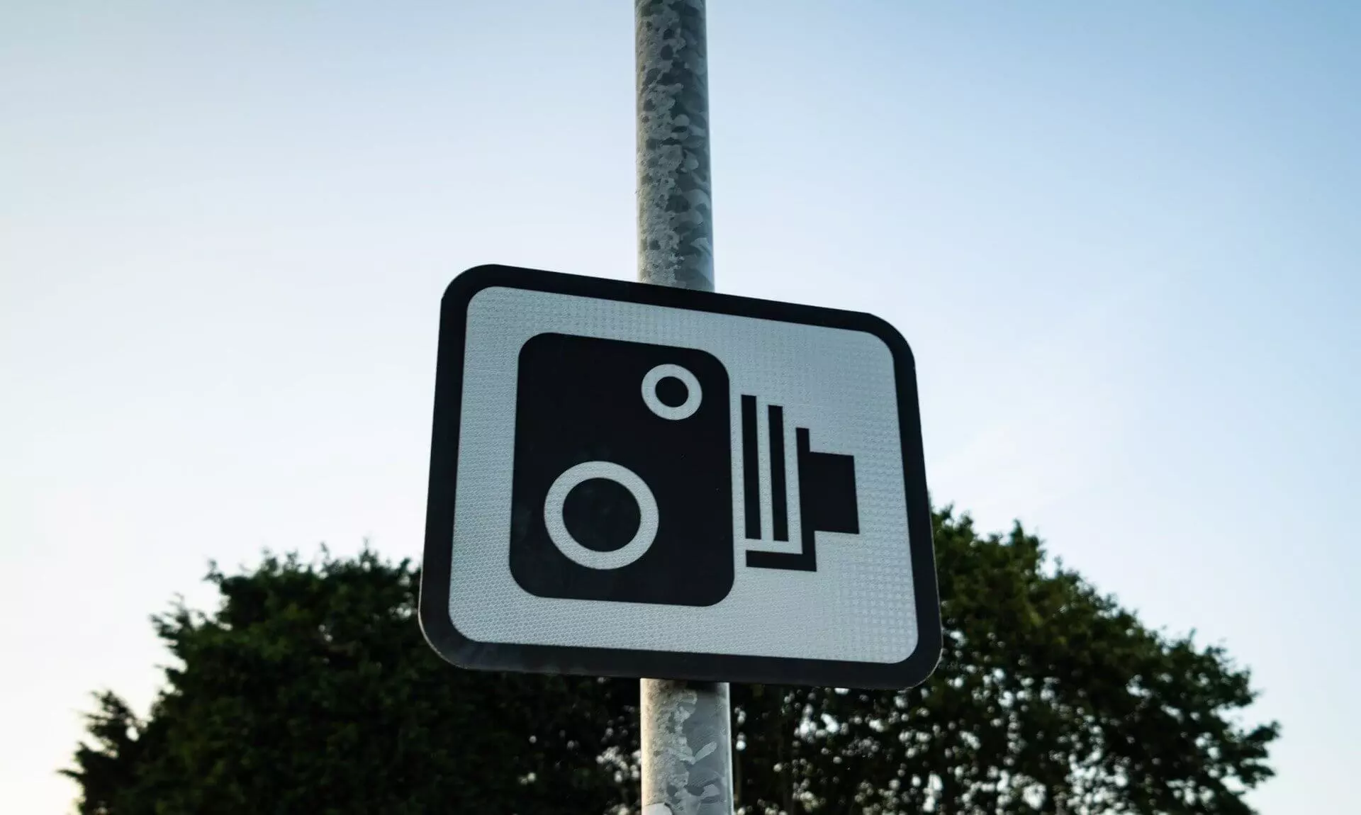 Speed camera warning sign on a pole