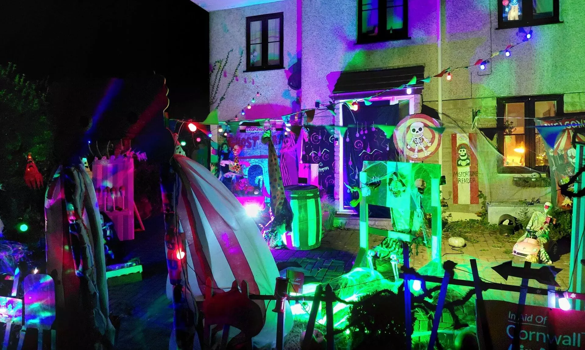 Halloween circus display lit in neon colours outside a house in St Day
