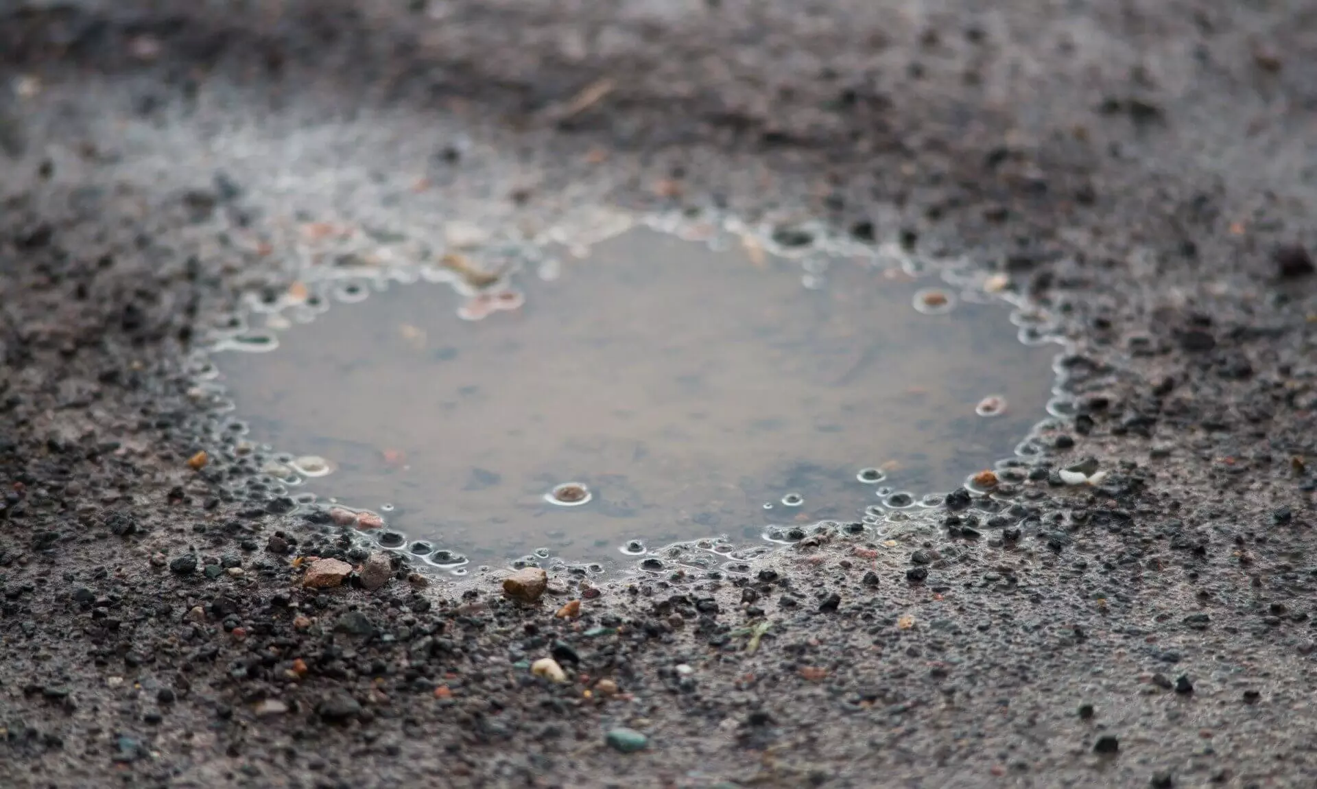 A water-filled pothole in a road surface