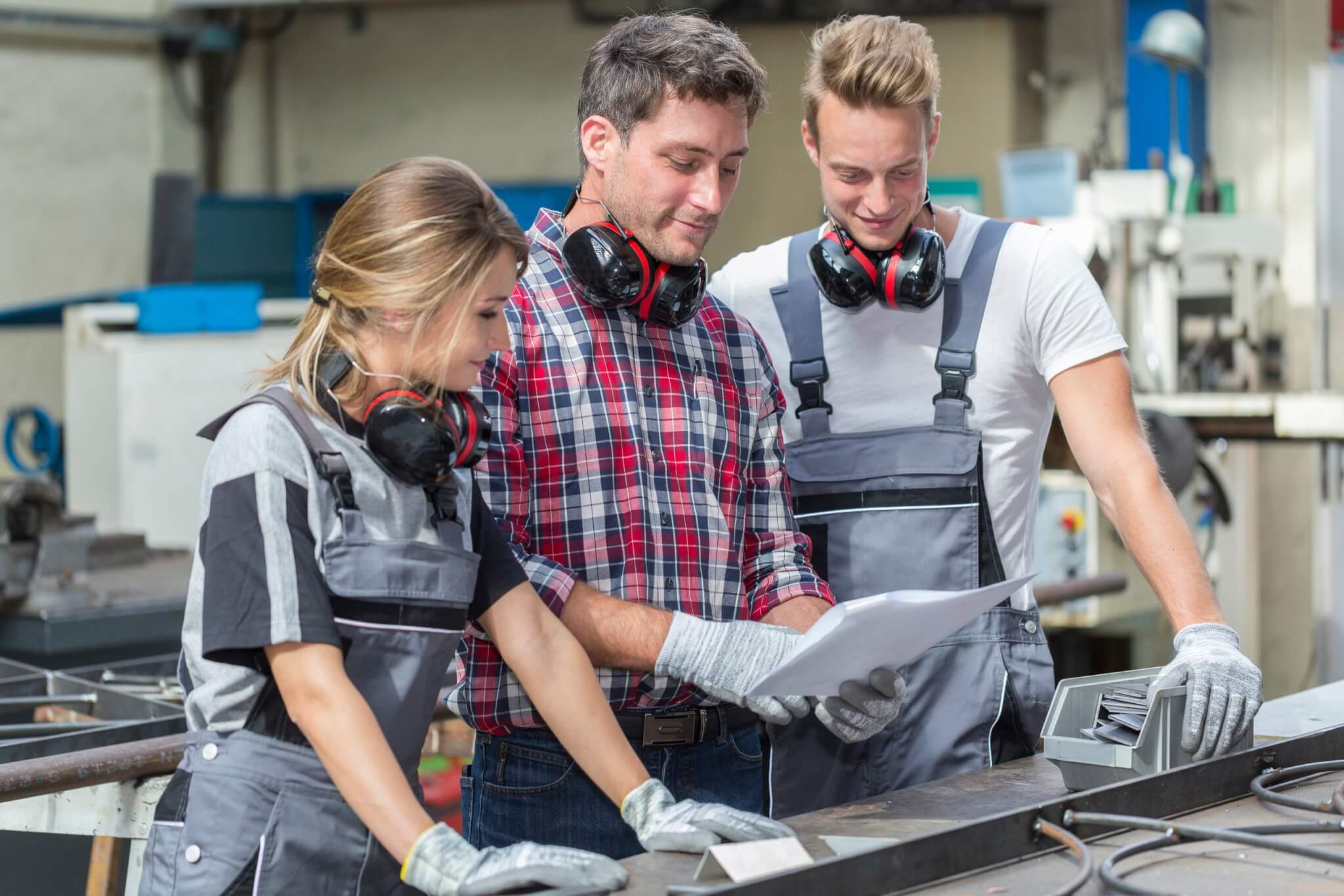 Young apprentices in a workshop looking over plans with a supervisor