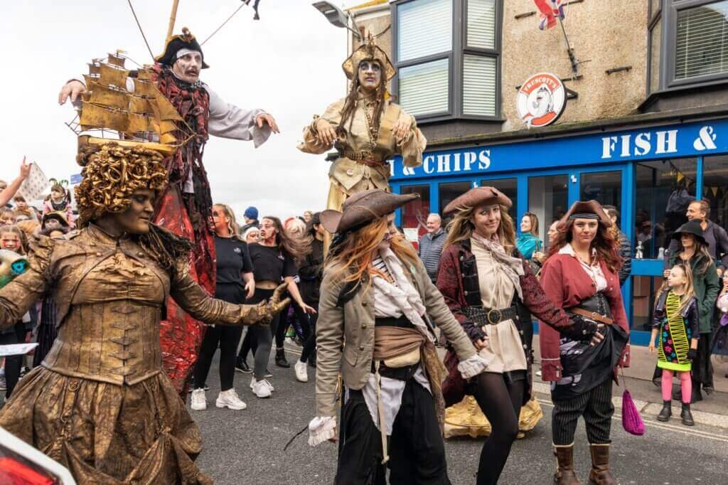 Pirate-costumed performers and stilt walkers outside a fish and chip shop in Newquay